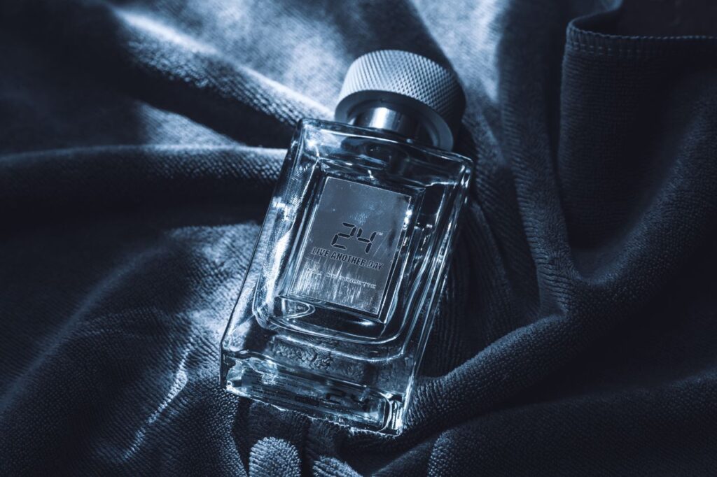 Glass perfume bottle with elegant design resting on a dark textured fabric, showcasing luxury and sophistication.