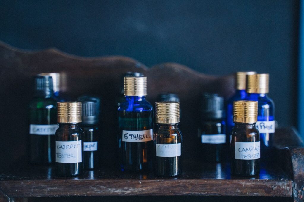 Close-up of glass bottles with essential oils arranged on a wooden shelf, labeled with various oils.