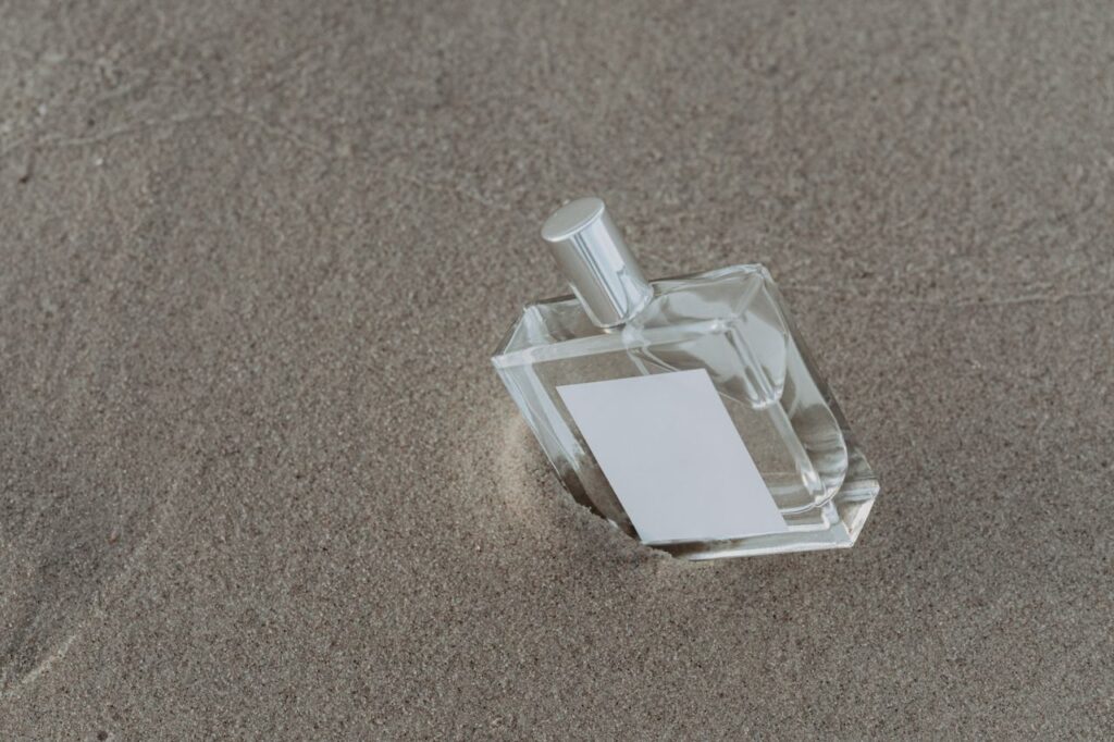 Minimalist perfume bottle resting on textured sand, capturing elegance and simplicity.